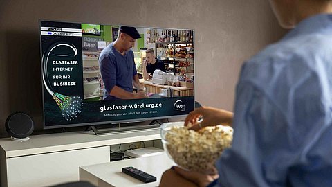 Mensch isst Popcorn während er Fernseher schaut