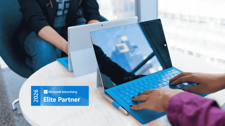 zwei Laptops auf dem Tisch und das Microsoft Elite Partner 2026 Badge