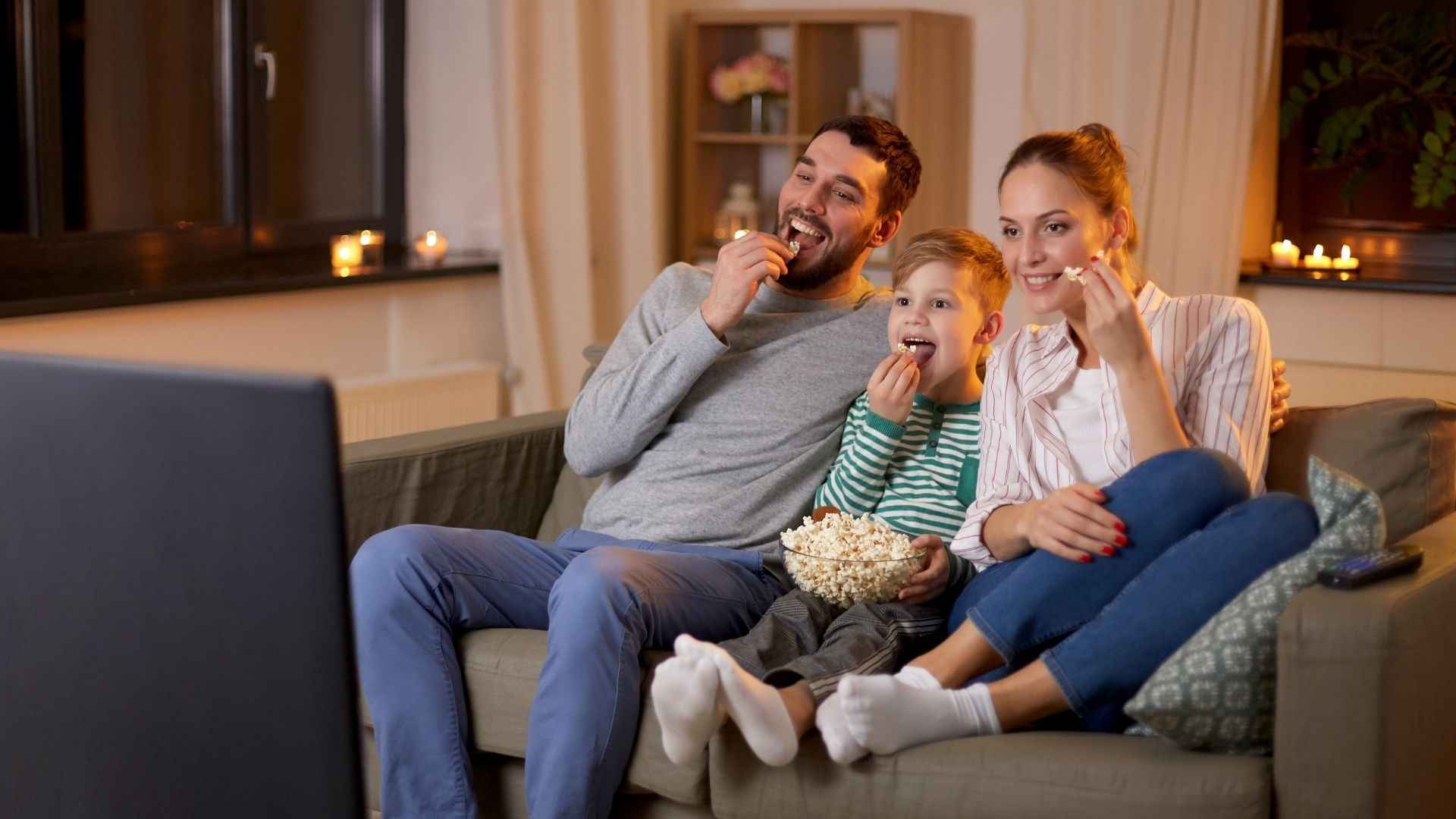 Familie schaut während dem Popcorn essen Fernseher