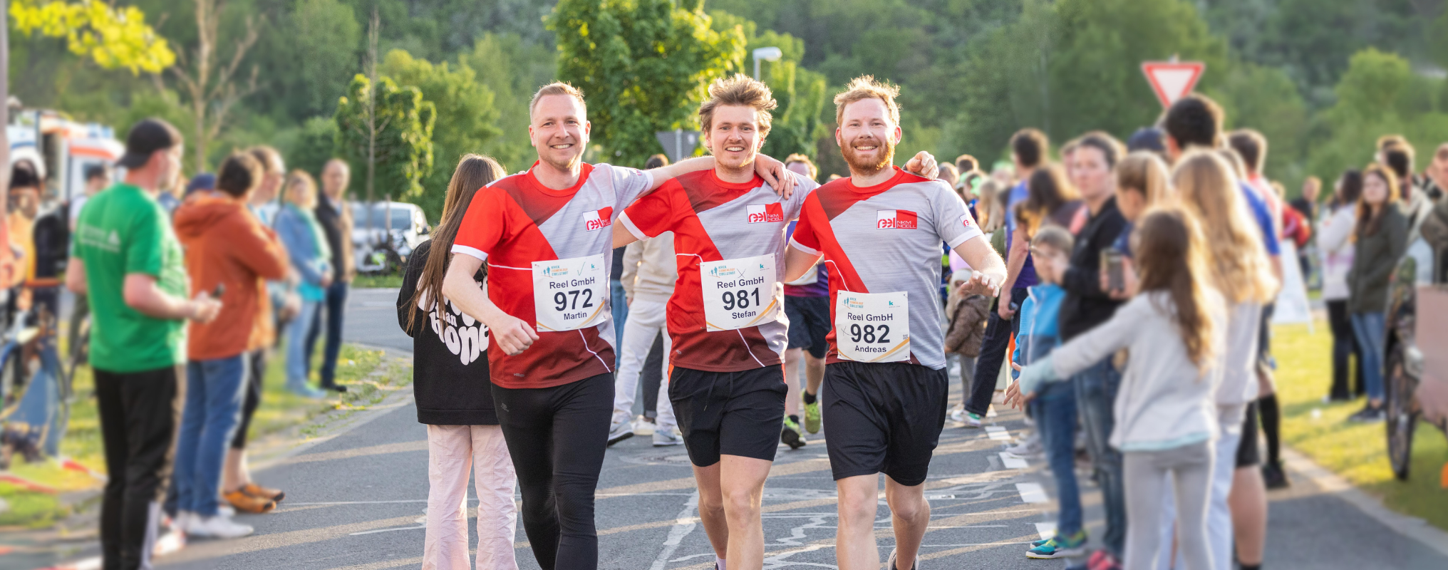 drei Läufer beim Krick Firmenlauf laufen Arm in Arm ins Ziel